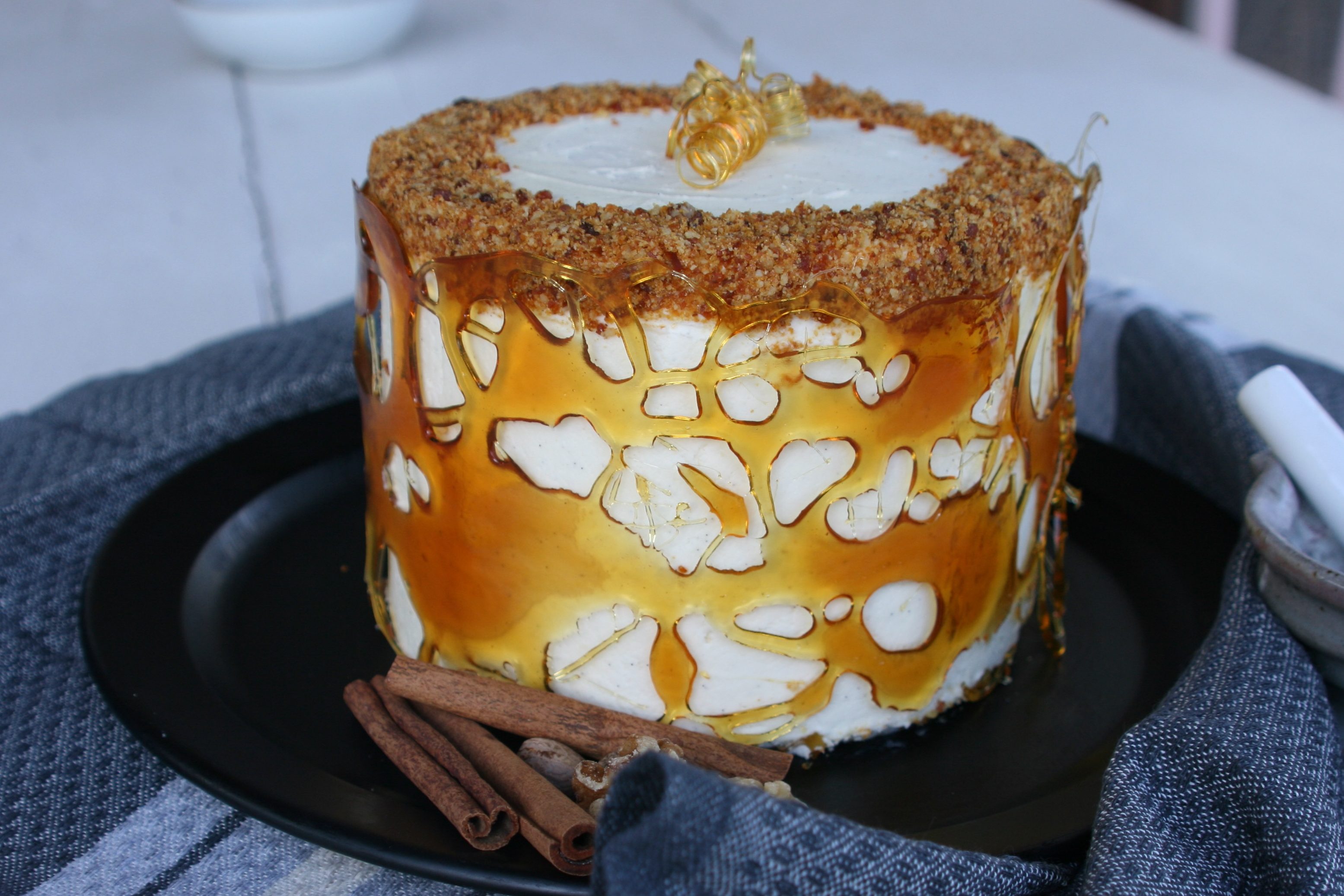 This walnut spice cake with coffee crème au beurre filling complements the cream cheese buttercream frosting and walnut praline topping. It also sports a unique caramel collar, giving it  a touch of artistic flair!