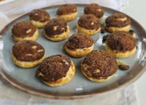 A plate of freshly baked pastries topped with a rich brown sugar crust, arranged neatly in two rows.